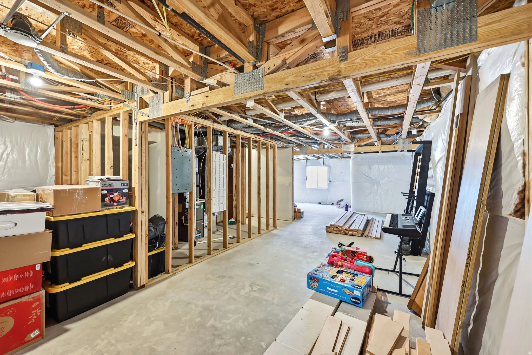 Unfinished basement featuring exposed wood framing, concrete flooring, and ample space for customization