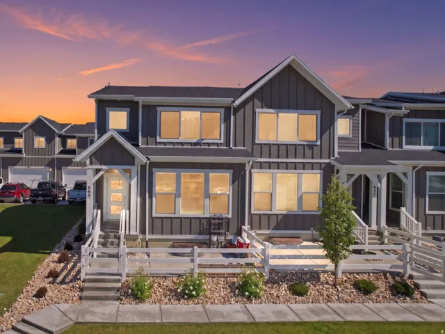 Modern gray facade with white trim, featuring multiple large windows and a front porch