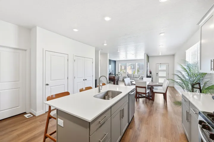 Kitchen island with integrated stainless steel sink, contemporary cabinetry, and wood-finish flooring