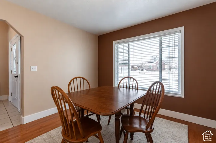 Window with horizontal blinds, wood-finish flooring, and white baseboards