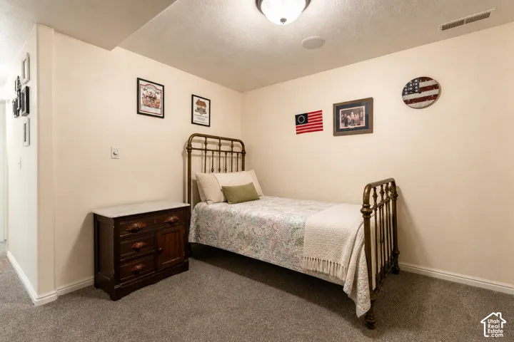 Carpeted room featuring a ceiling-mounted light fixture and a wall-mounted vent