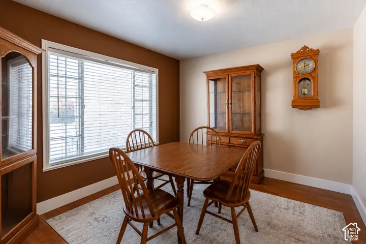 Spacious room featuring a large window with white blinds, wood-finish flooring, and white trim