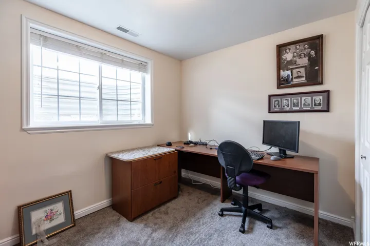 Room featuring a large window with white trim, light beige wall paint, and gray carpet flooring