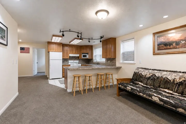 Open-concept living area featuring a kitchen with wood cabinetry, a breakfast bar with stone-finish countertop, and full-size appliances