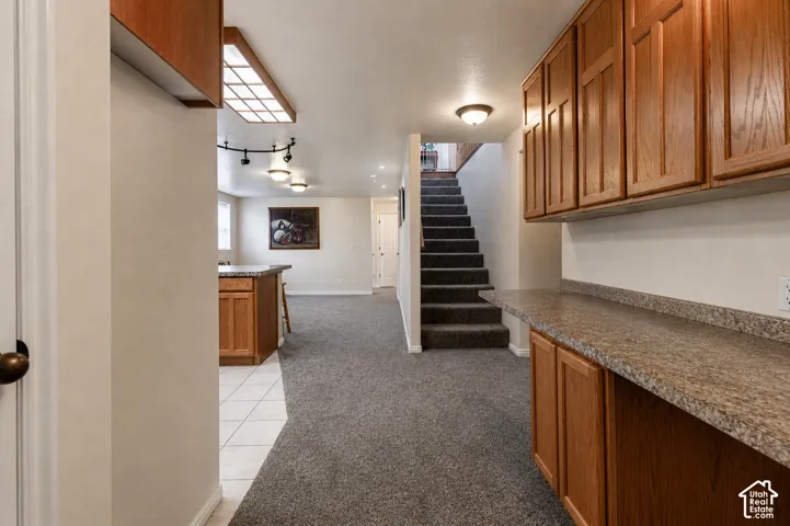 Lower level featuring wood-finish cabinetry, a patterned countertop, and integrated ceiling lighting