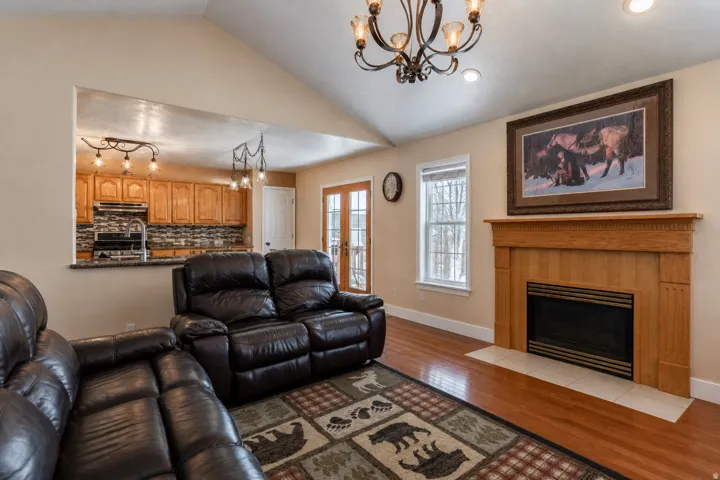 Living area featuring a natural wood fireplace with a tiled hearth, cathedral ceiling, and wood-finish flooring