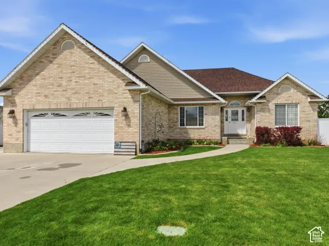 Light brick exterior featuring a white garage door, concrete driveway, and a manicured lawn