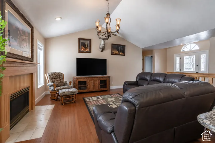 Living area featuring vaulted ceilings, wood-finish flooring, and a fireplace with a wood mantel