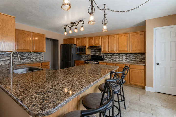 Kitchen featuring a large island with a stone-finish countertop and an undermount sink