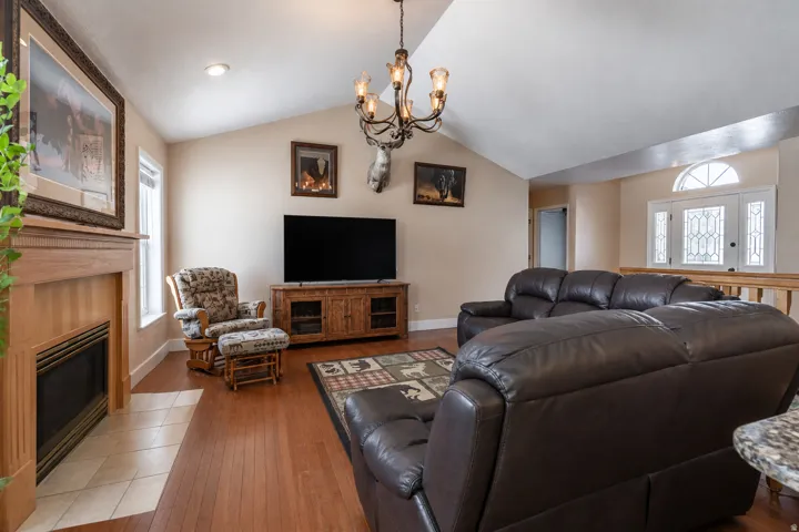 Living area featuring vaulted ceilings, wood-finish flooring, and a fireplace with a wood mantel