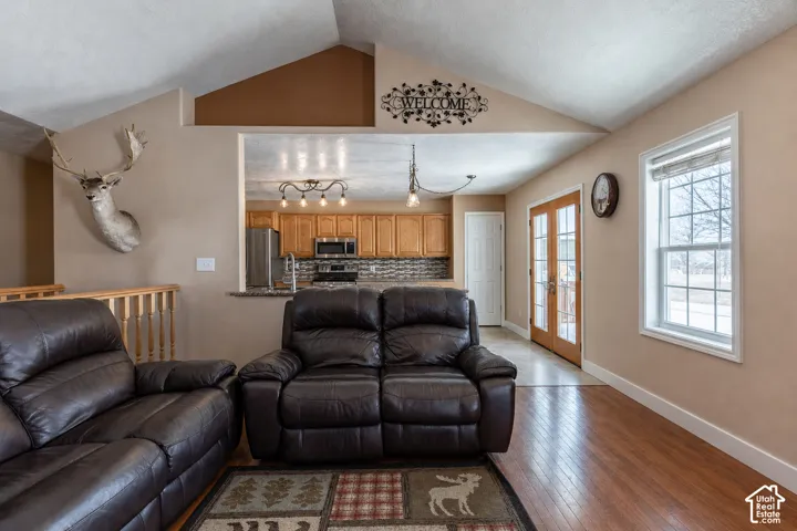 Vaulted ceiling living area featuring wood-finish flooring and ample natural light from a large window