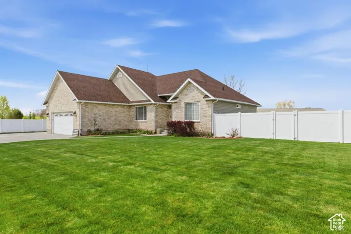 Expansive green lawn surrounds a brick and siding home with an attached two-car garage