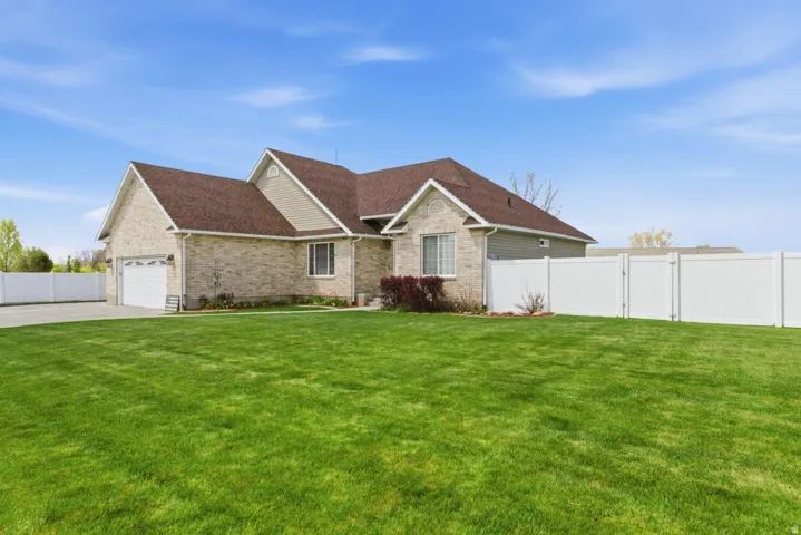 Expansive green lawn surrounds a brick and siding home with an attached two-car garage