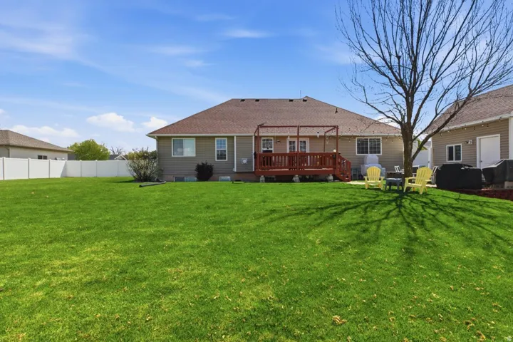 Expansive backyard featuring a manicured lawn, a full wooden deck, and a white privacy fence