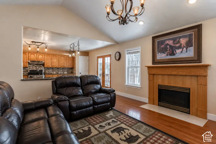 Living area featuring a natural wood fireplace with a tiled hearth, cathedral ceiling, and wood-finish flooring