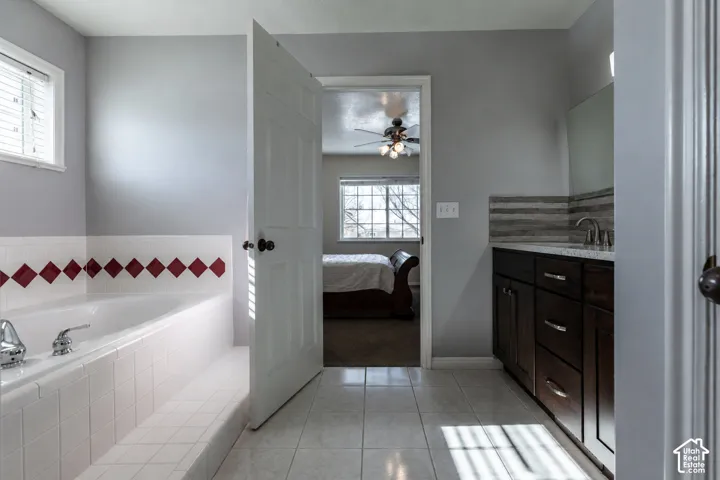 Bathroom featuring a built-in soaking tub with white tile surround and red accent tiles
