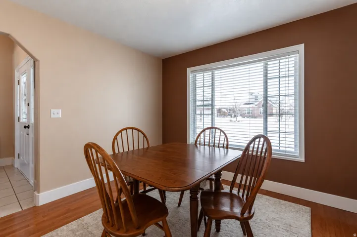 Window with horizontal blinds, wood-finish flooring, and white baseboards