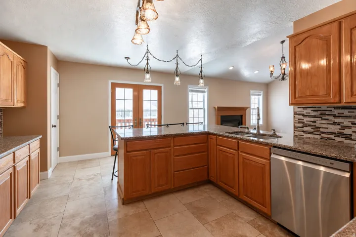 Kitchen featuring wood cabinetry, granite countertops, tile flooring, a mosaic tile backsplash, and stainless steel appliances