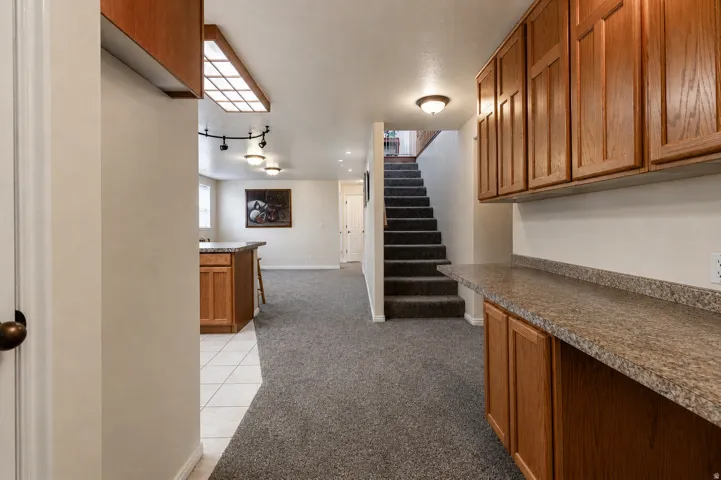Lower level featuring wood-finish cabinetry, a patterned countertop, and integrated ceiling lighting