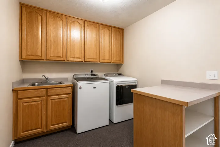 Laundry room featuring wood cabinetry, integrated sink, and countertop space