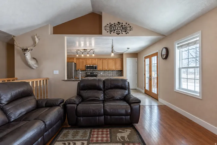 Vaulted ceiling living area featuring wood-finish flooring and ample natural light from a large window