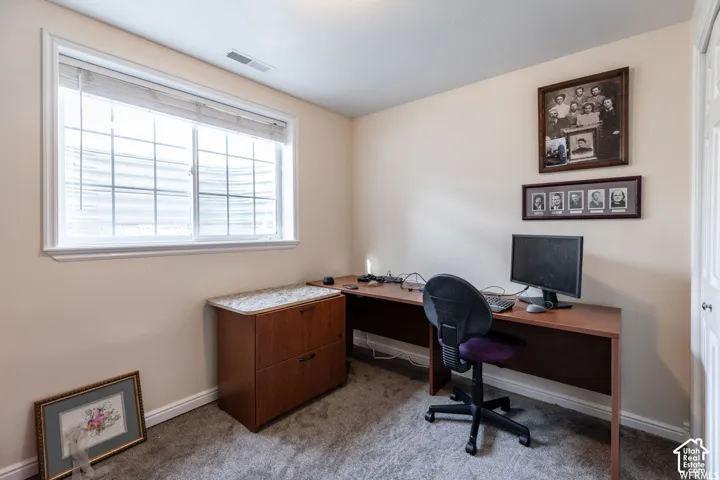 Room featuring a large window with white trim, light beige wall paint, and gray carpet flooring
