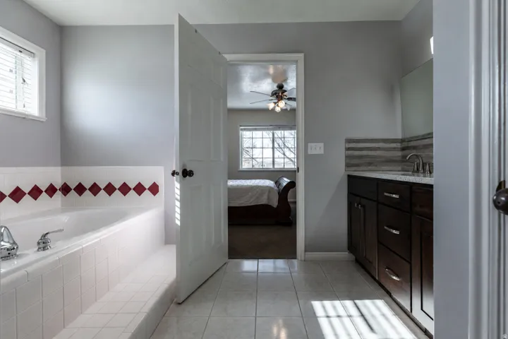 Bathroom featuring a built-in soaking tub with white tile surround and red accent tiles
