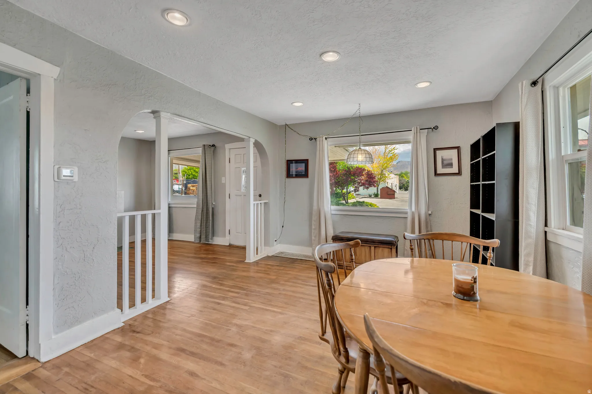 Open dining area featuring wood-finish flooring, recessed lighting, and an arched entry