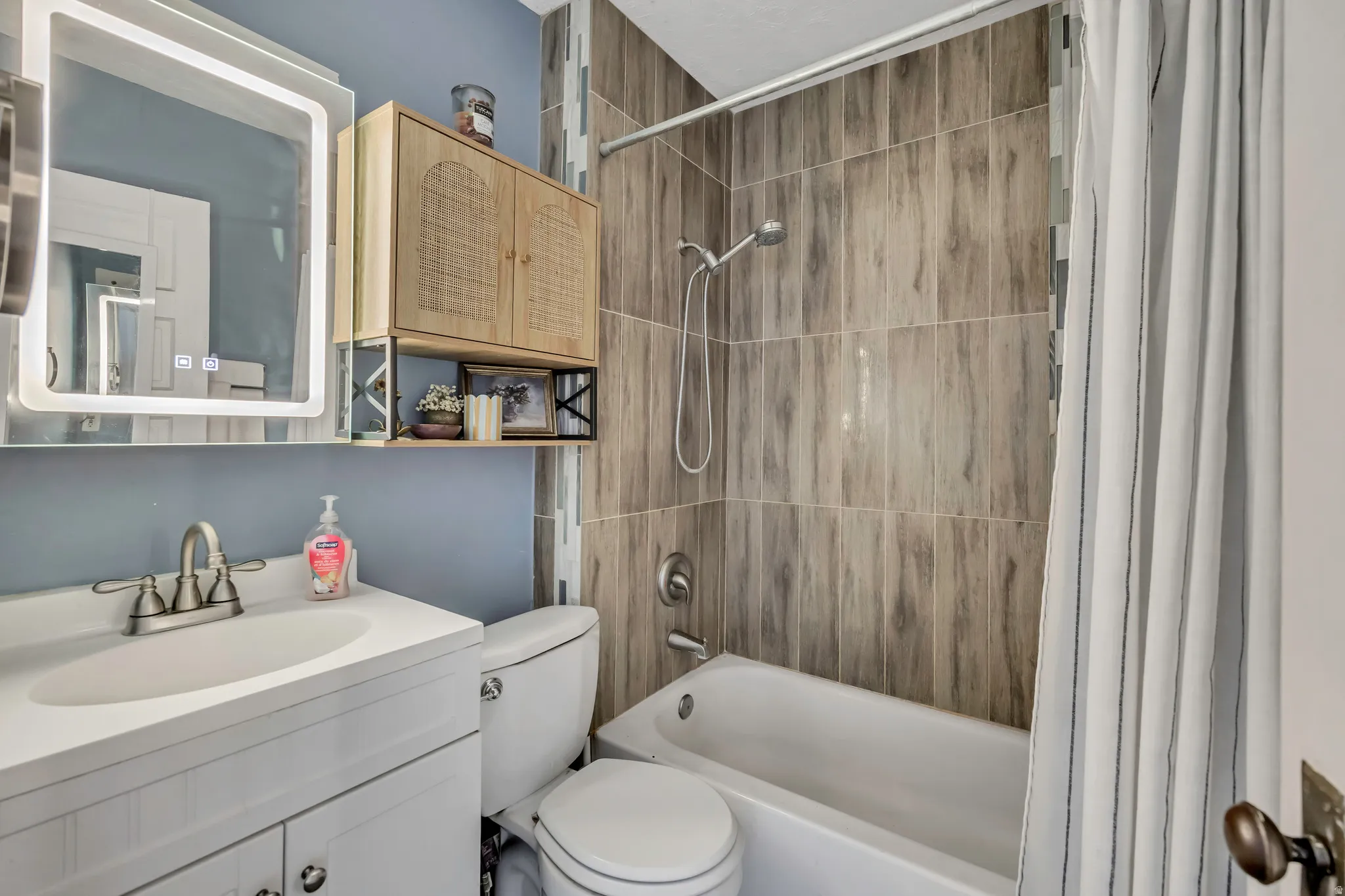 Bathroom featuring a white vanity with integrated sink, brushed nickel faucet, and an illuminated mirror