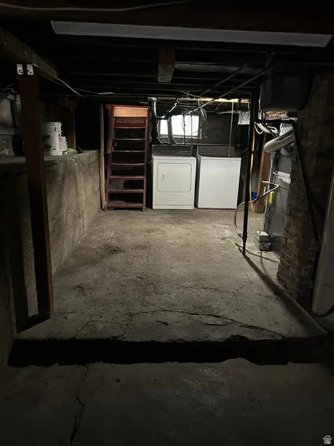 Basement laundry area featuring concrete flooring and exposed ceiling joists