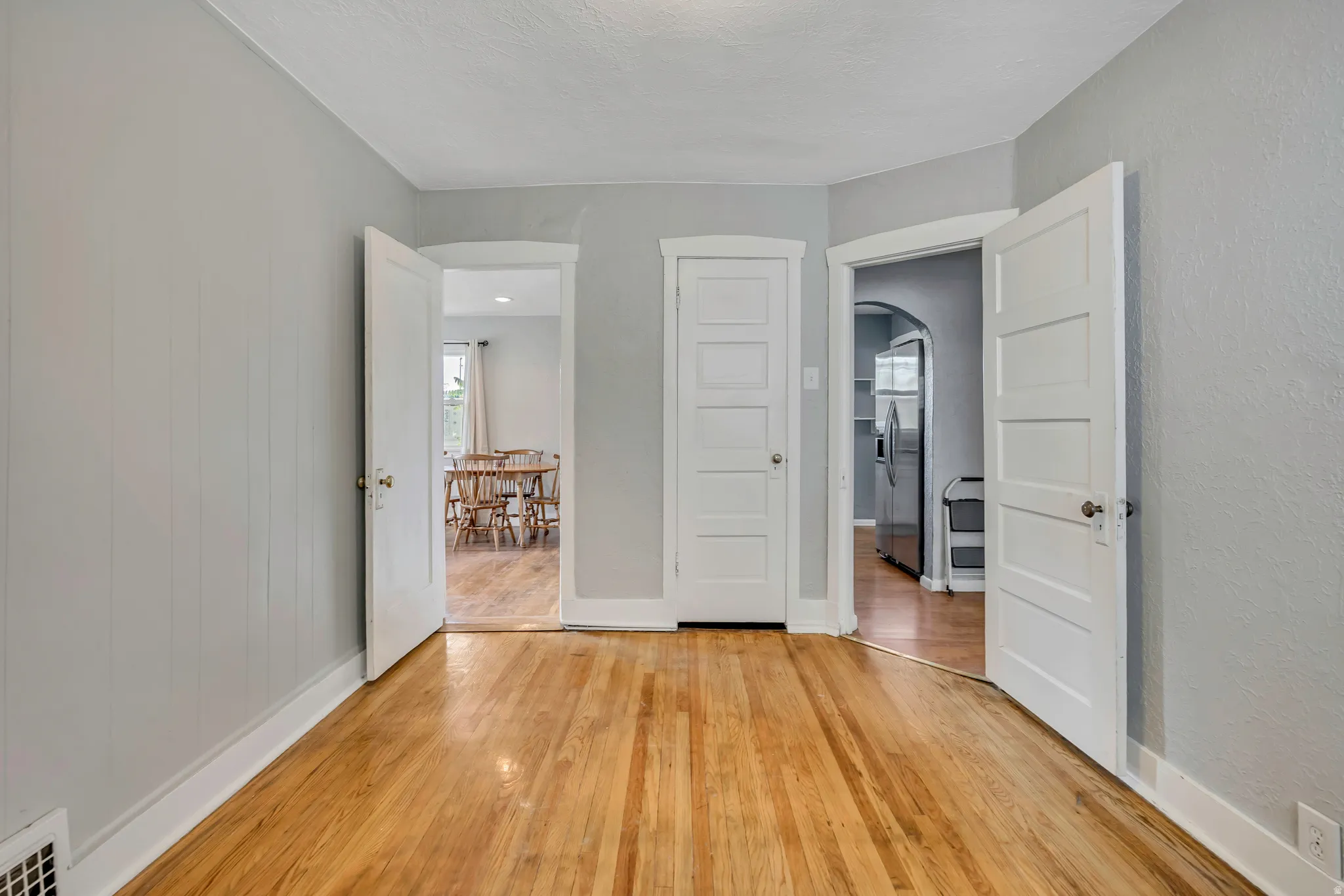 Hardwood flooring throughout, light gray wall paint, white trim, and paneled interior doors