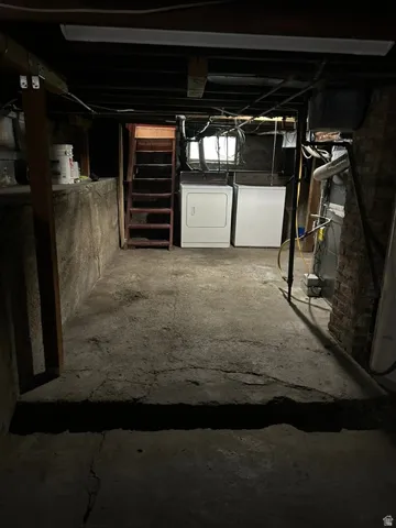 Basement laundry area featuring concrete flooring and exposed ceiling joists