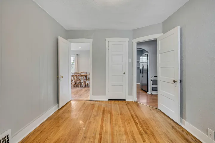 Hardwood flooring throughout, light gray wall paint, white trim, and paneled interior doors