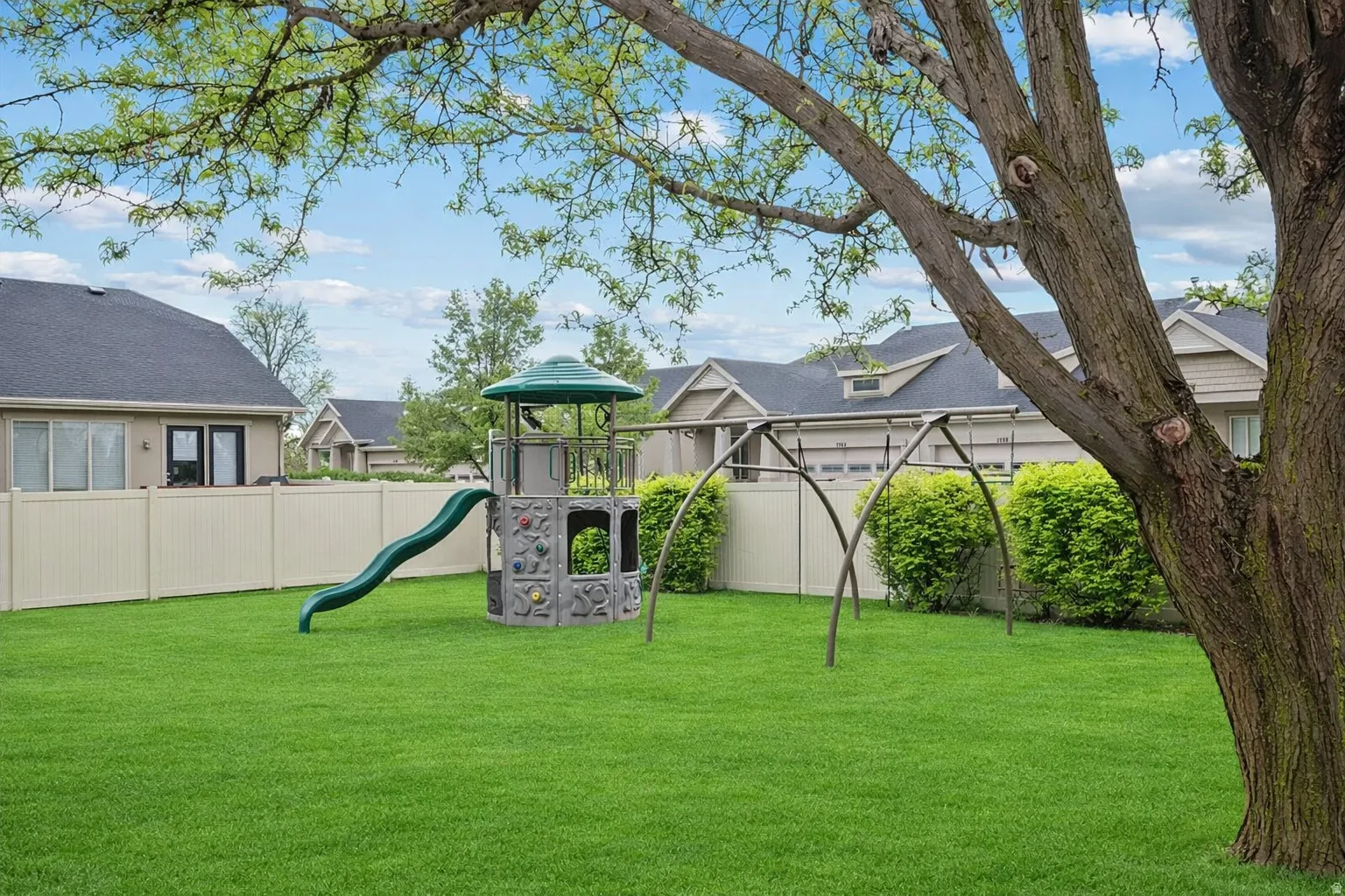 Expansive green lawn featuring a multi-level play structure with a slide and climbing wall
