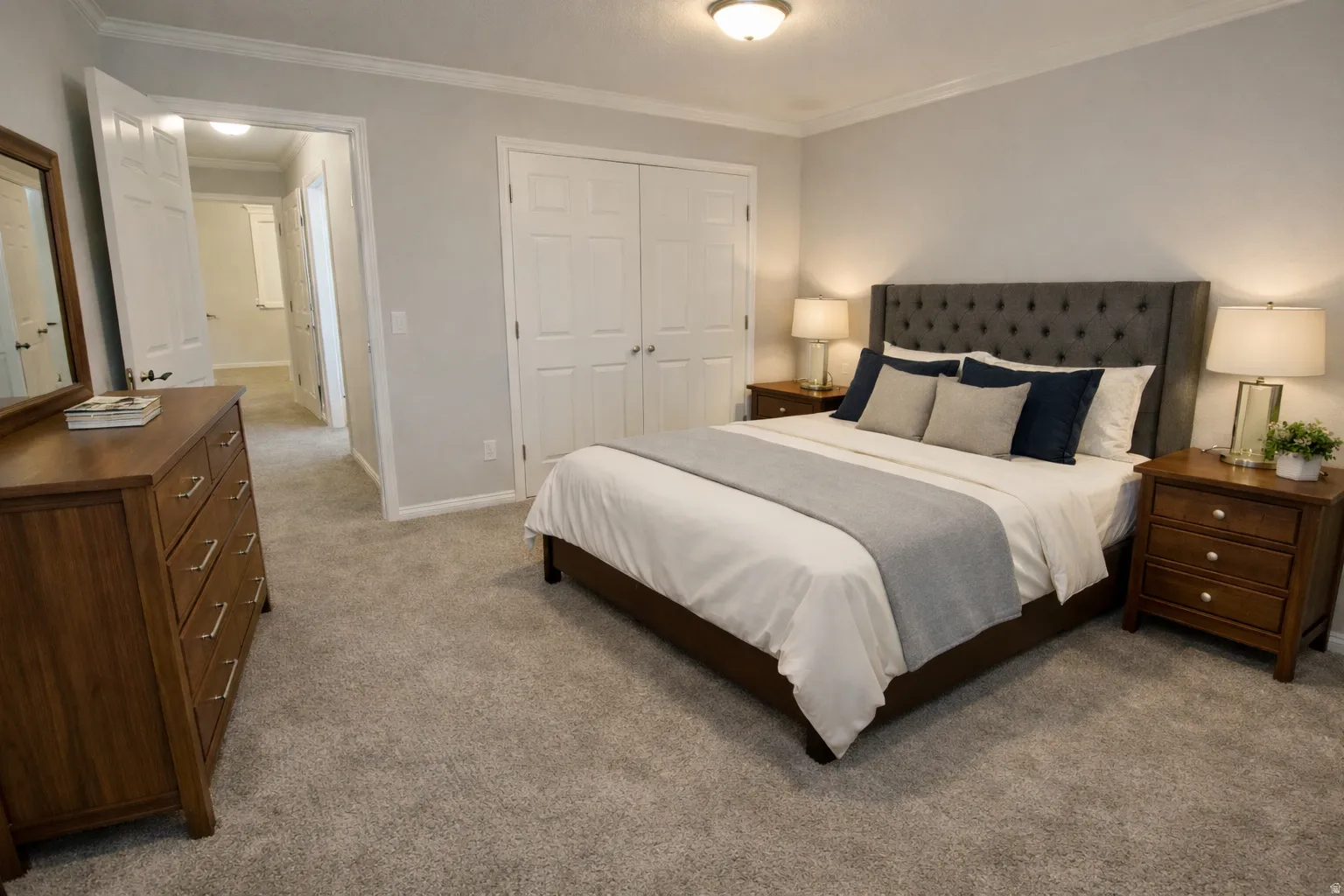 Carpeted bedroom featuring a double-door closet, crown molding, and a flush mount ceiling light
