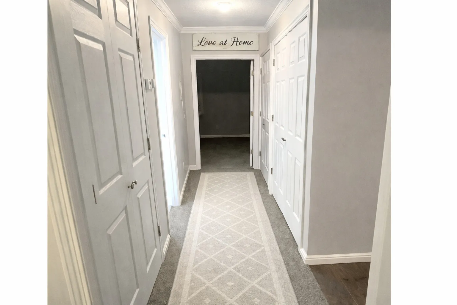 Hallway featuring paneled doors, crown molding, light gray wall paint, and gray carpet flooring