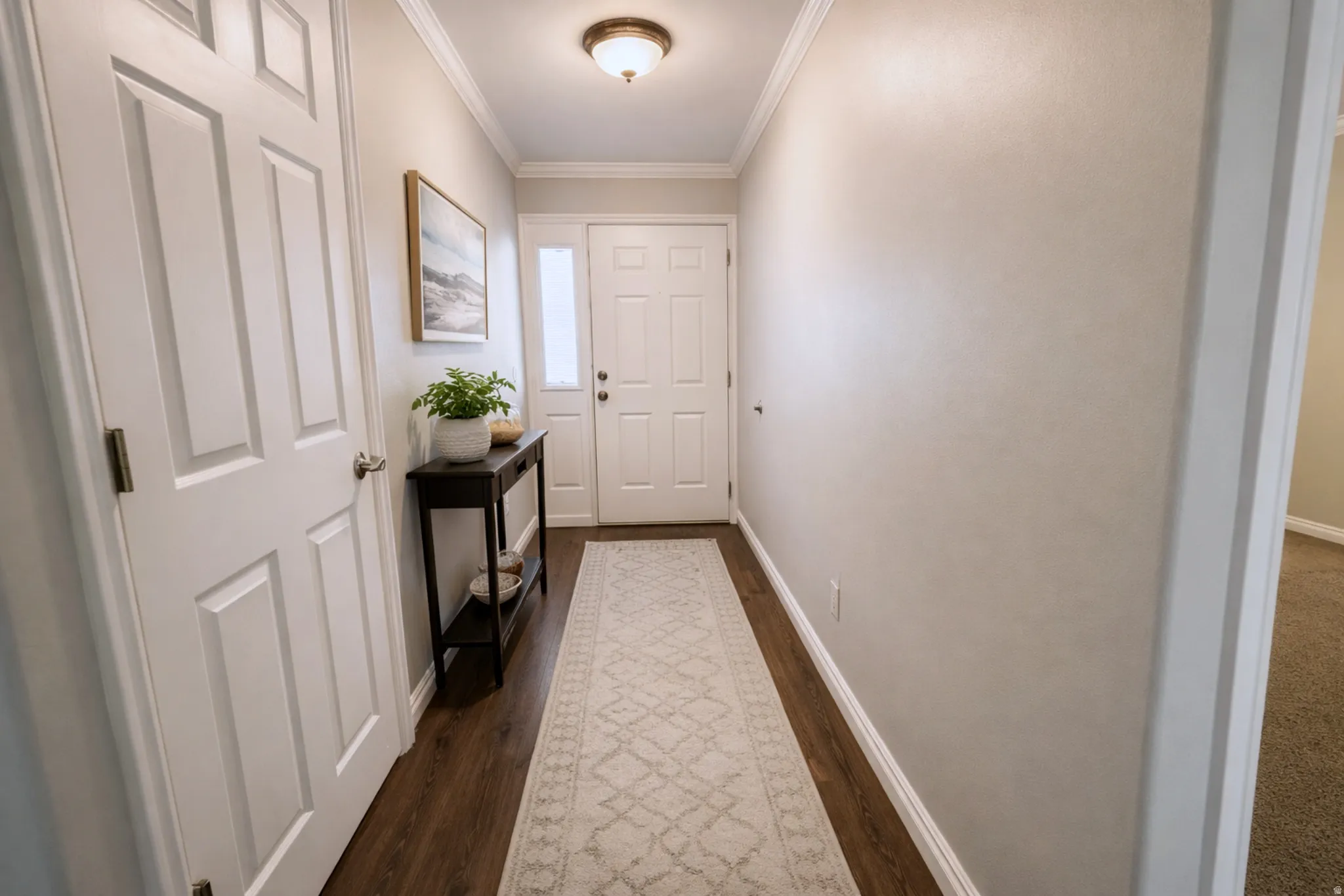 Entryway featuring wood-finish flooring, white paneled doors, and crown molding