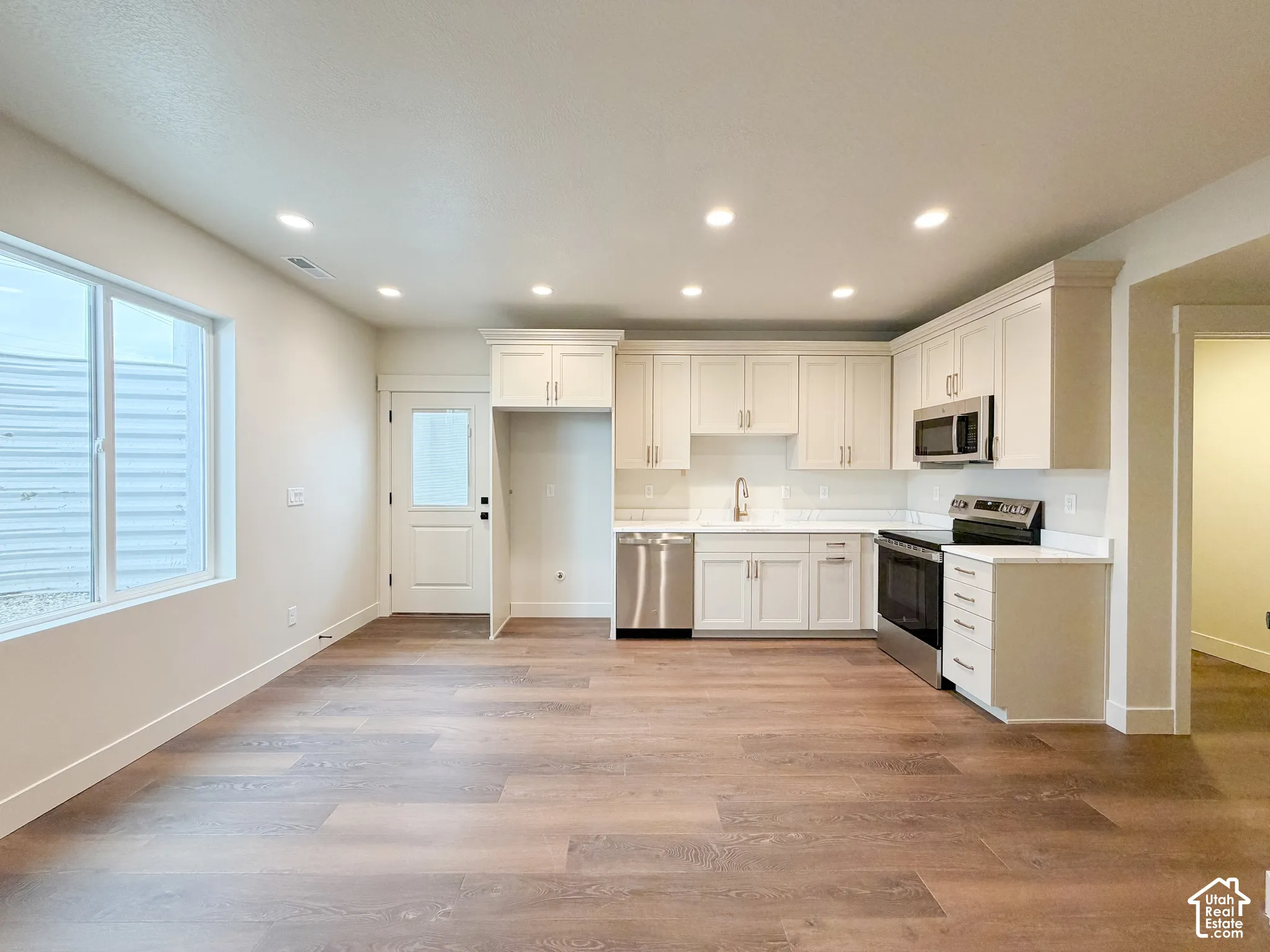 Open-concept living space with wood-finish flooring, recessed lighting, and a large window
