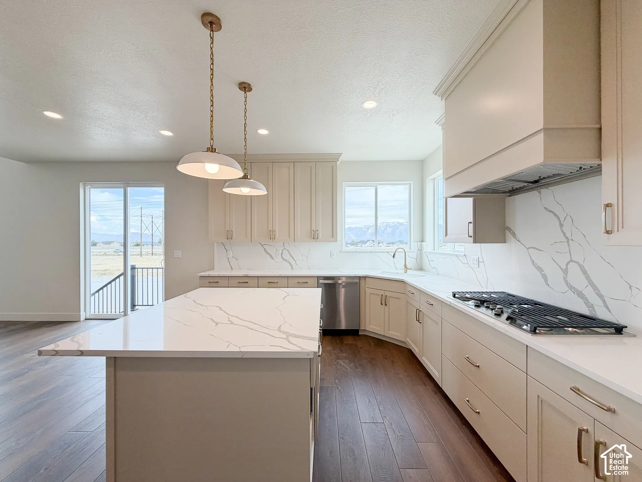 Kitchen with L-shaped cabinetry, island, stainless steel appliances, and integrated gas cooktop
