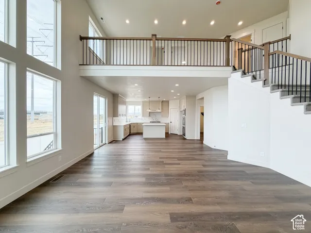 Two-story living space featuring wood-finish flooring, a contemporary staircase with iron balusters, and large picture windows