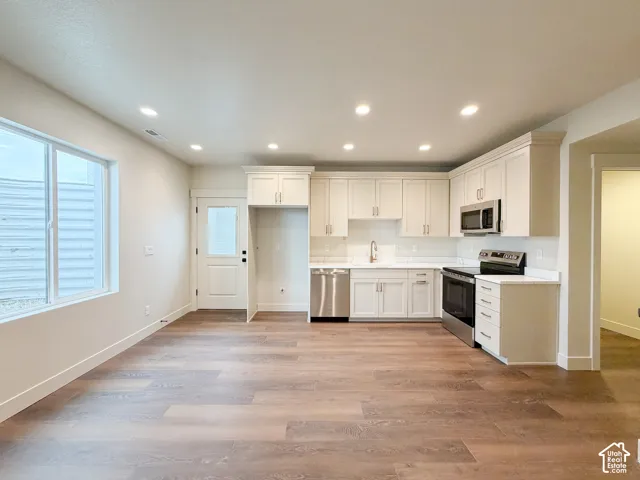 Open-concept living space with wood-finish flooring, recessed lighting, and a large window