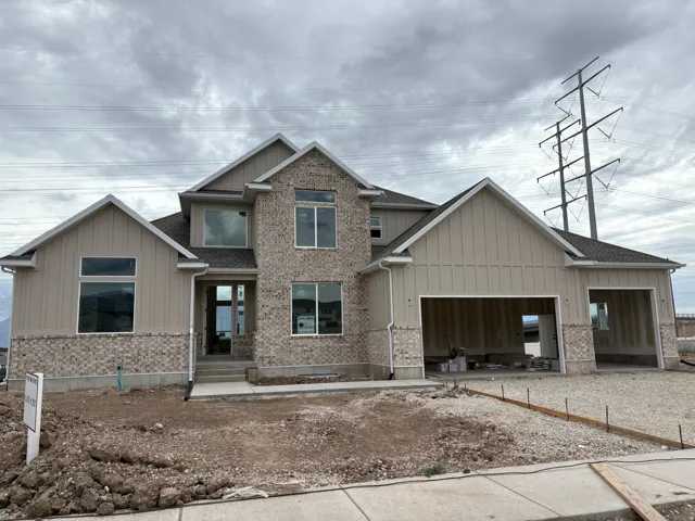 Contemporary new construction home featuring a multi-tone brick facade and vertical panel siding