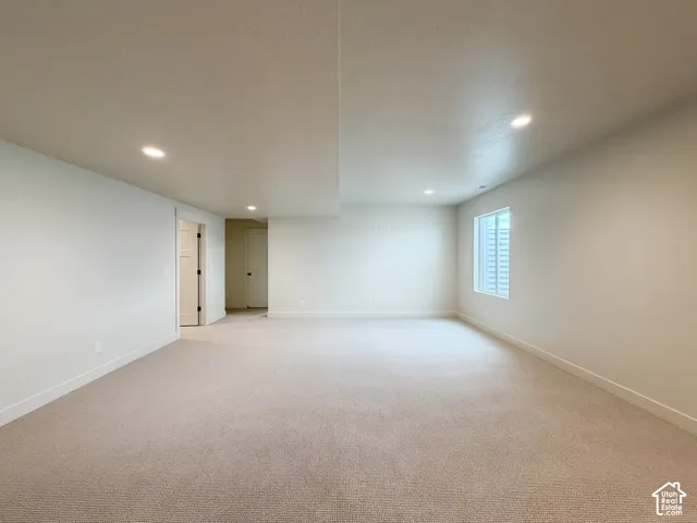 Expansive carpeted room with neutral wall tones, recessed lighting, and a window with a light well