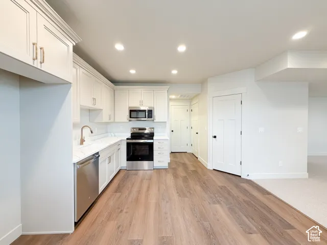Kitchen featuring white shaker cabinetry, stainless steel appliances, wood-finish flooring, recessed lighting, and white countertops