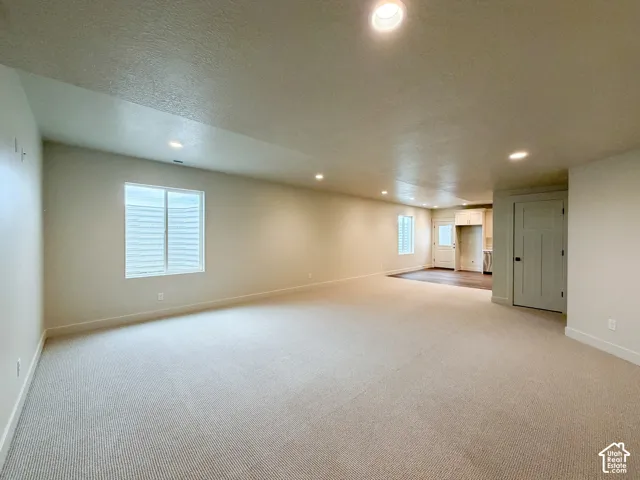 Open-concept living space featuring recessed lighting, a window with blinds, light-toned carpeting, and a craftsman-style interior door