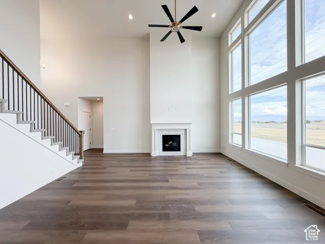 Two-story living space featuring wood-finish flooring, a contemporary fireplace with a classic mantel, and expansive floor-to-ceiling windows
