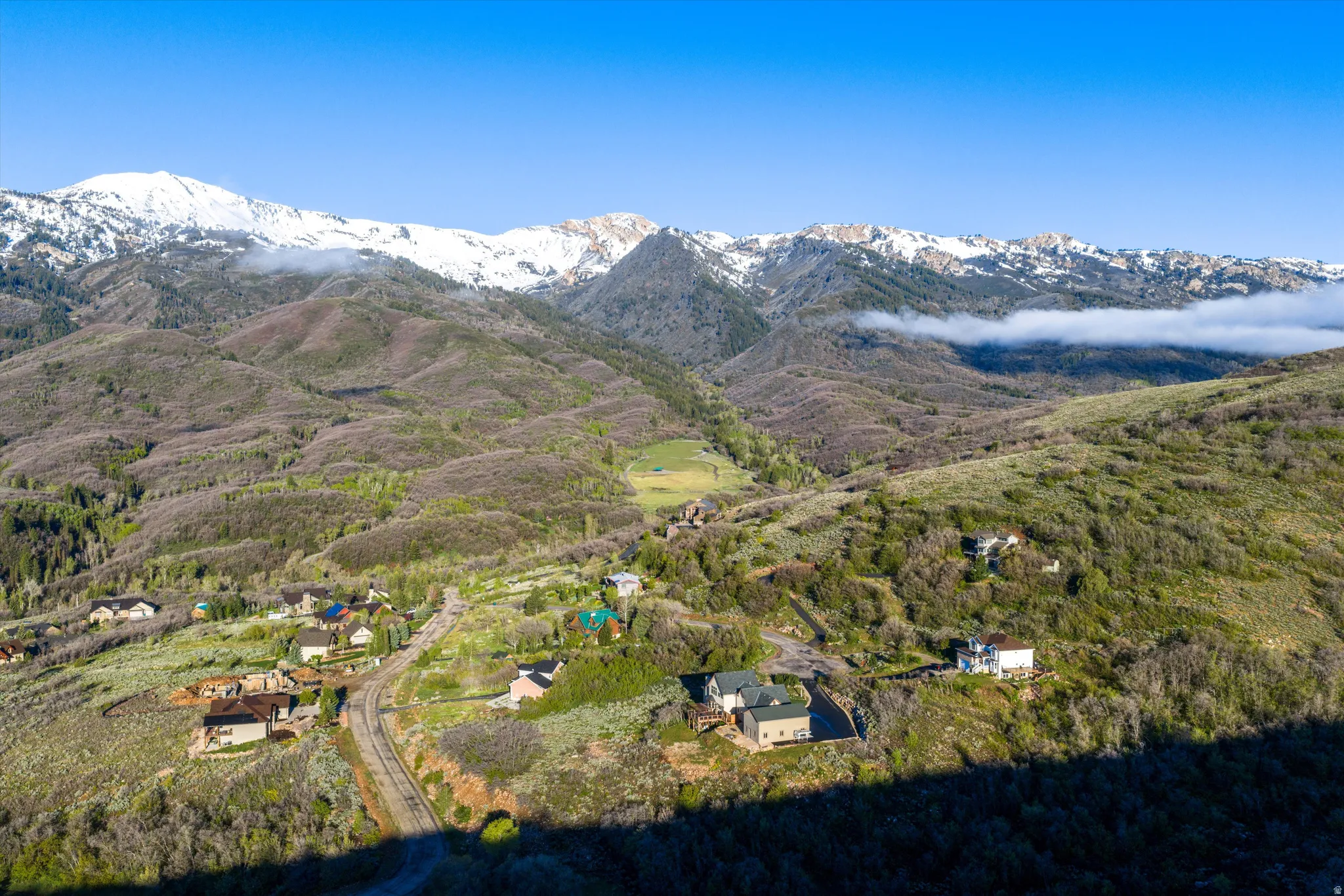 Expansive mountain landscape featuring distant snow-capped peaks and scattered residential properties