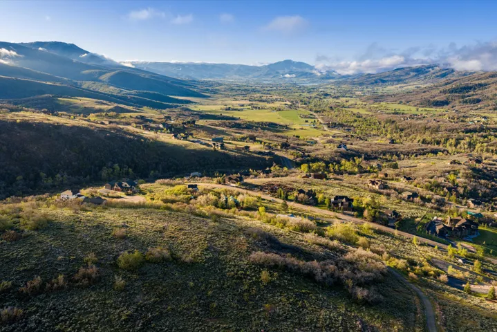 Expansive valley landscape featuring rolling hills, distant mountains, and scattered residential properties