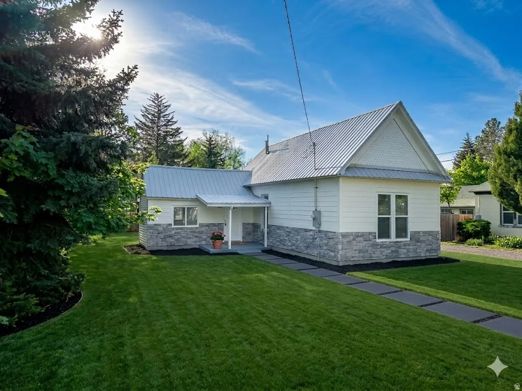 Single-story home featuring a metal roof, light-toned siding, and a stone veneer foundation