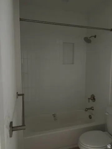Bathtub with white tile surround, integrated shower niche, and brushed nickel fixtures